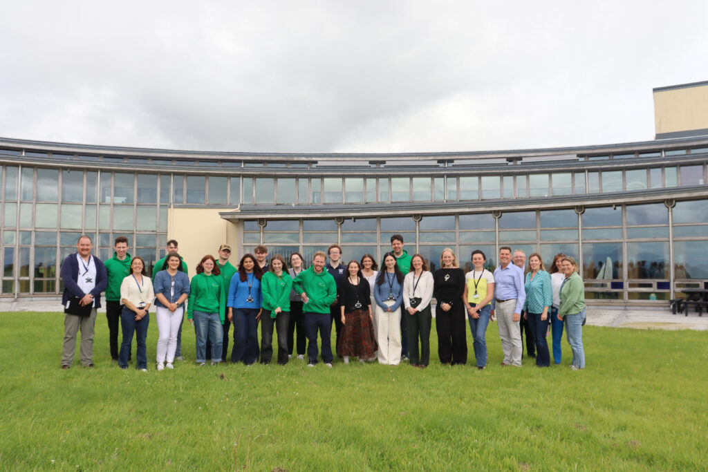 A group photo of bursars and supervisors on the background of the Marine Institute Headquarters