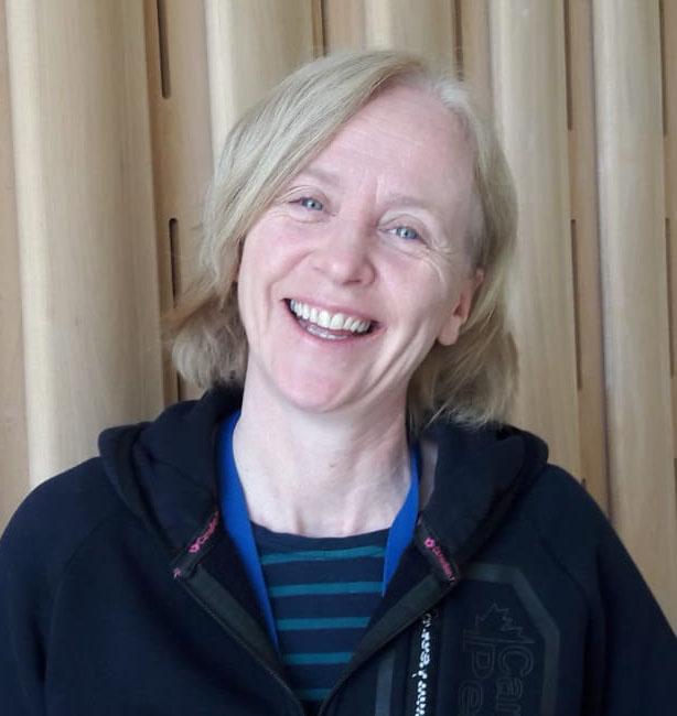 Dr Caroline Cusack smiling in front of a wood-panelled wall.